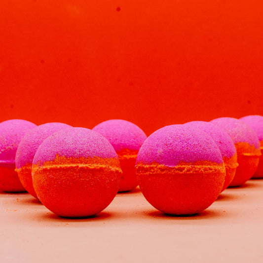Row of pink and orange bath bombs on a red background