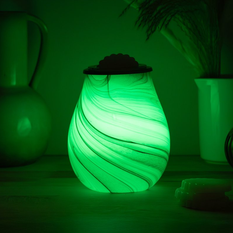 Glowing green wax melt warmer in a dark room with plants and furniture.