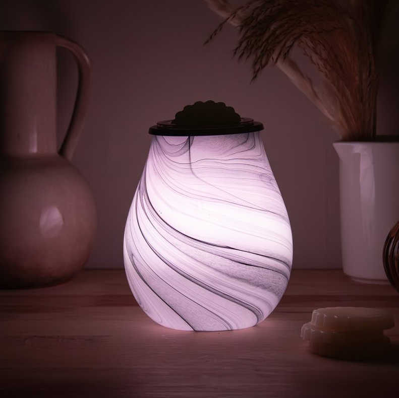Marble-patterned wax melt warmer on a wooden surface with soft lighting
