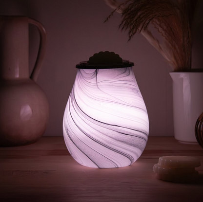 Marble-patterned wax melt warmer on a wooden surface with soft lighting