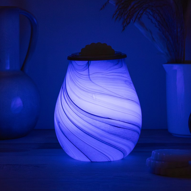 Decorative wax melt warmer wavy pattern glowing in a dark room.