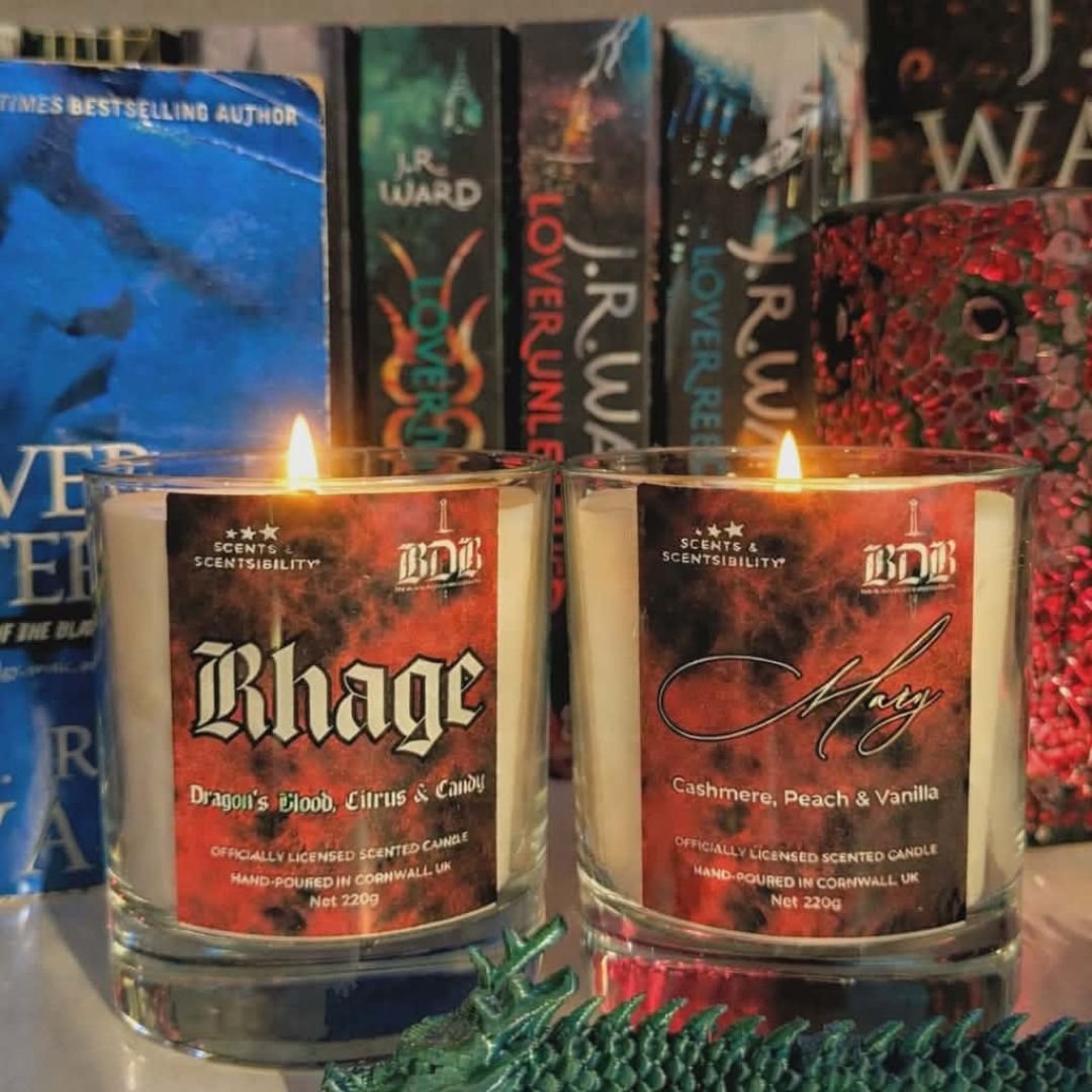 Two scented candles with labels 'Rhage' and 'Mary' in front of books.
