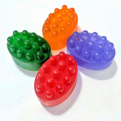 Four colourful massage soap bars in green, orange, purple and red with raised textured massage bumps.