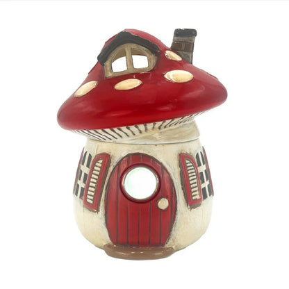 Decorative mushroom-shaped wax melt warmer with a red cap and door on a white background
