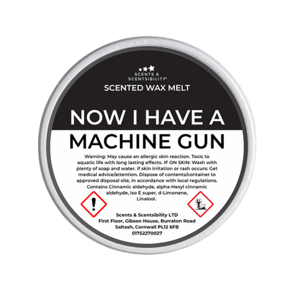 Scented wax melt container labeled 'Now I Have a Machine Gun' with warning text on a green background.