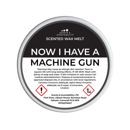Scented wax melt container labeled 'Now I Have a Machine Gun' with warning text on a green background.