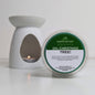 Scented wax melt container labeled 'Oh, Christmas Tree!' next to a white wax warmer with a lit candle.