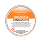 Scented wax melt container labeled 'Orange & Cinnamon' on a green background