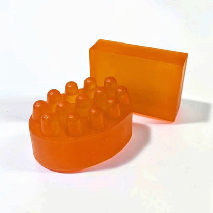 Orange massage soap bar with raised massage bumps alongside a matching rectangular soap bar.