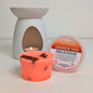 Neon orange scented wax melt with a white wax melt burner and container on a light background