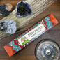 Palo Santo incense packaging with decorative elements on a wooden surface with crystals and a metal dish.