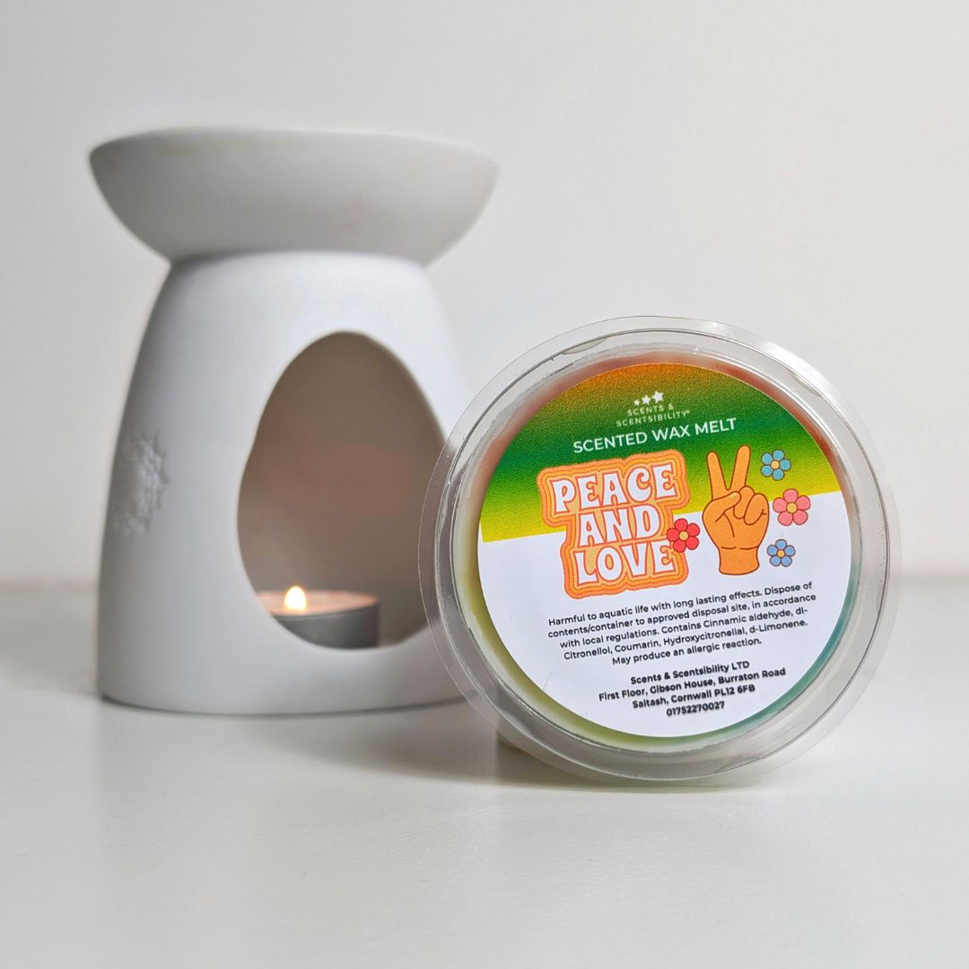 Scented wax melt container with 'Peace and Love' label next to a white wax warmer on a light background
