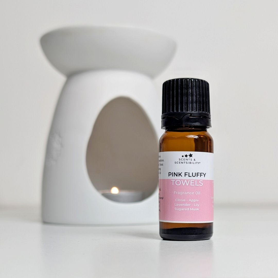 Bottle of 'Pink Fluffy Towels' fragrance oil with a white wax melt burner in the background.