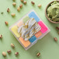 Set of colorful wax melts in a clear container with 'Plush Pistachio' branding on a green background with pistachios and ice cream