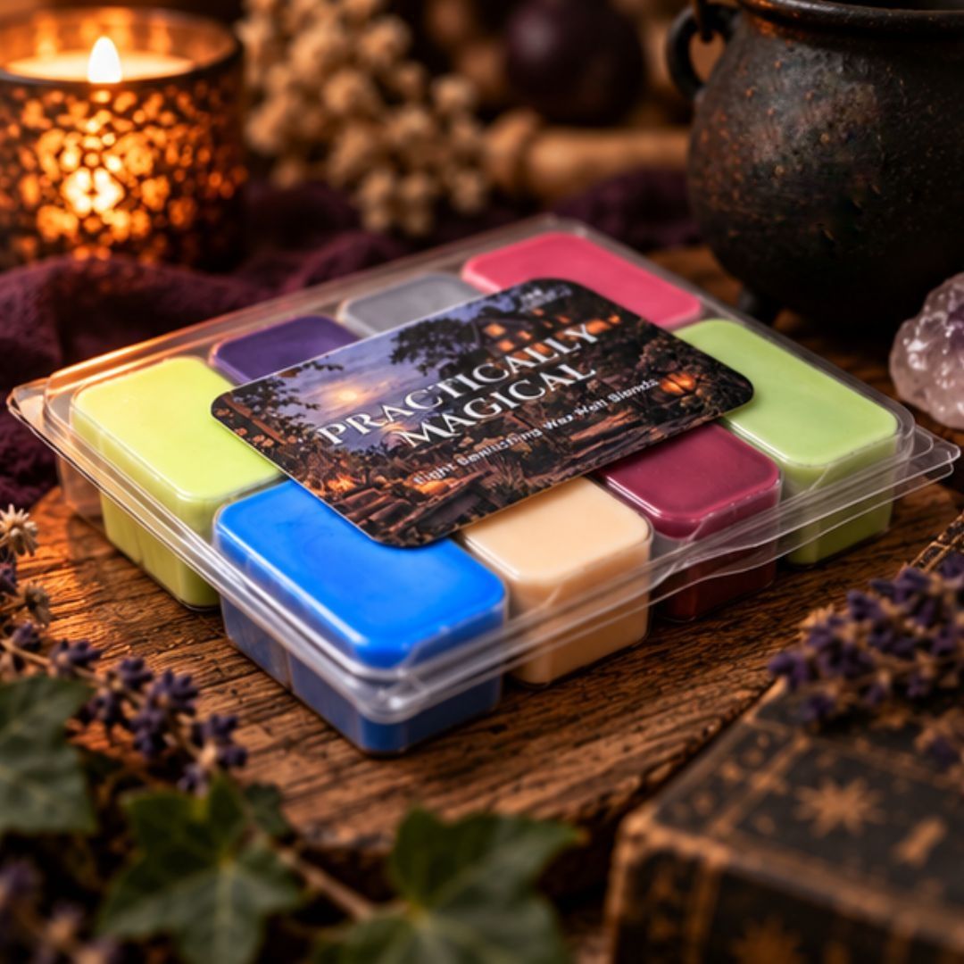 A clear plastic clamshell container holding multiple square wax melts in assorted colors, with a dark label reading 'Practically Magical' placed on top. The product sits on a rustic wooden surface surrounded by candles, dried flowers, and other cozy decorative props.