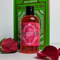 A bottle of liquid soap with a red label, rose petals and a green book. 