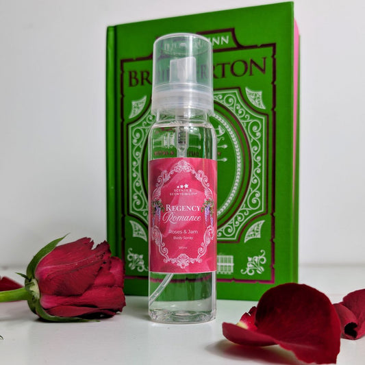Clear spray bottle with pink label in front of a green book and red roses.