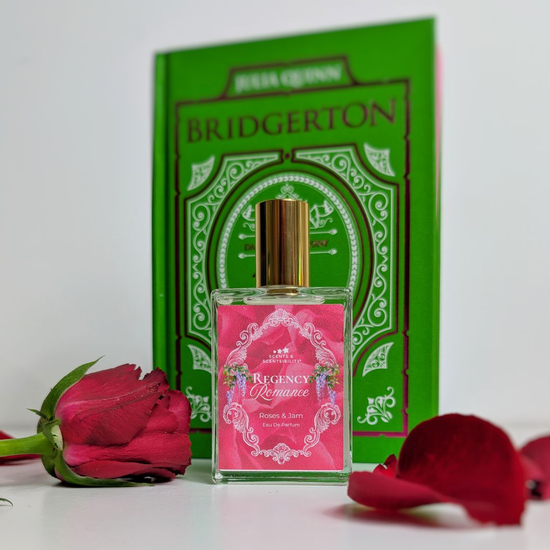 Perfume bottle labeled 'Regency Romance' with a red rose and book titled 'Bridgerton' in the background.