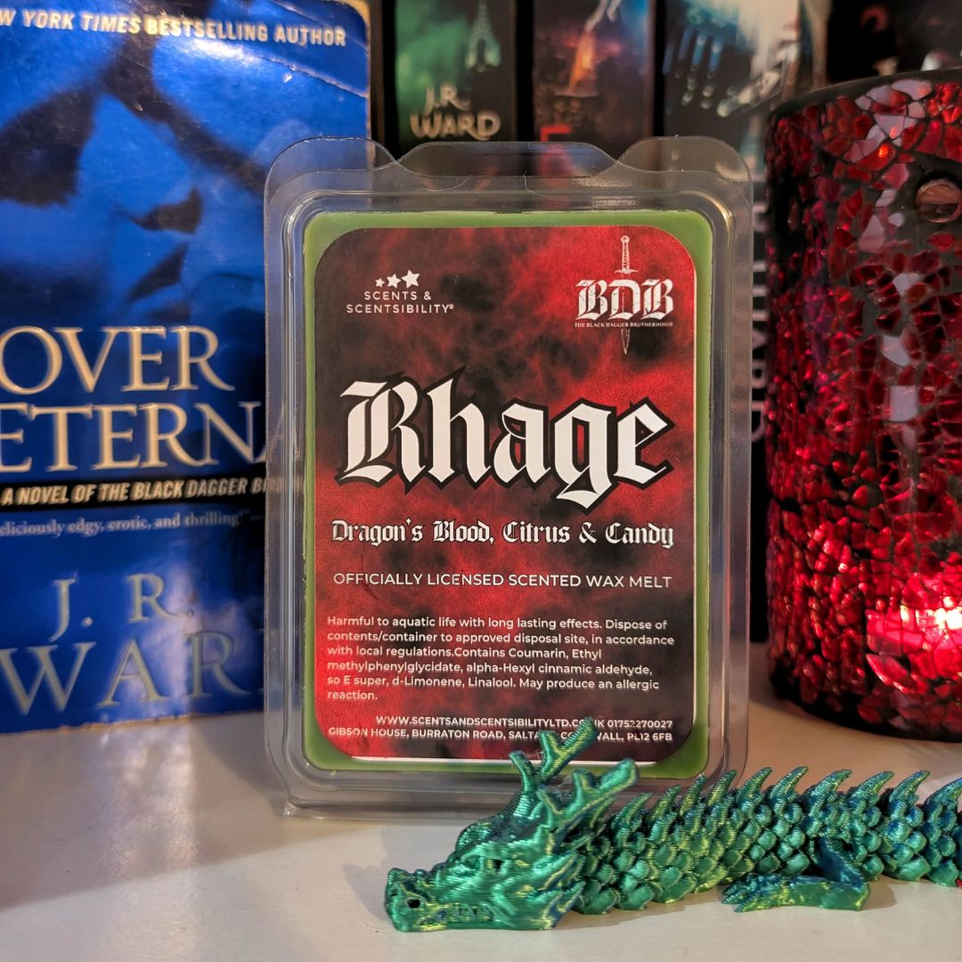 Scented wax melt packaging with 'Rhage' branding in front of books and a decorative dragon figurine.