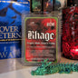 Scented wax melt packaging with 'Rhage' branding in front of books and a decorative dragon figurine.