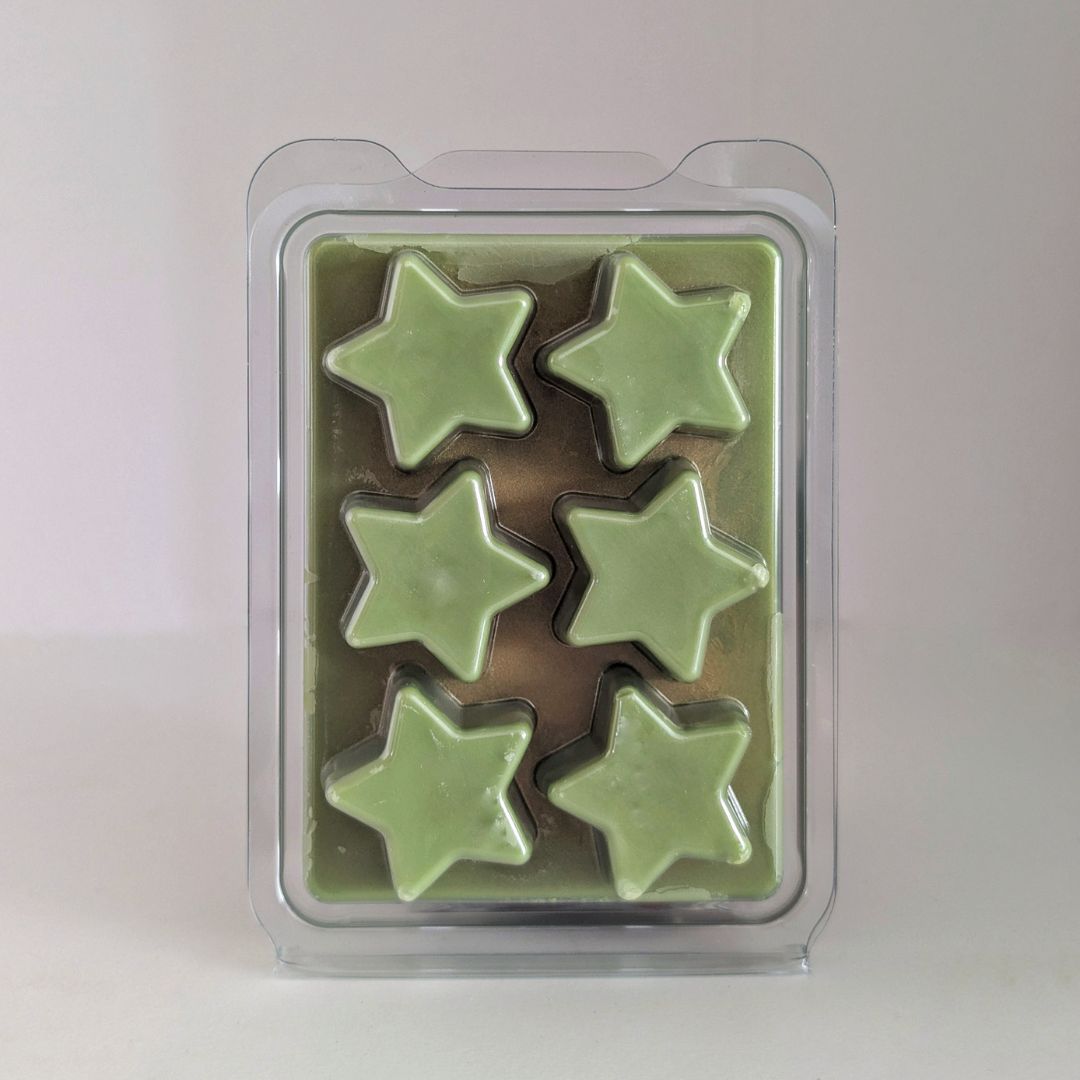 Pack of star-shaped green wax melts in clear packaging on a light background
