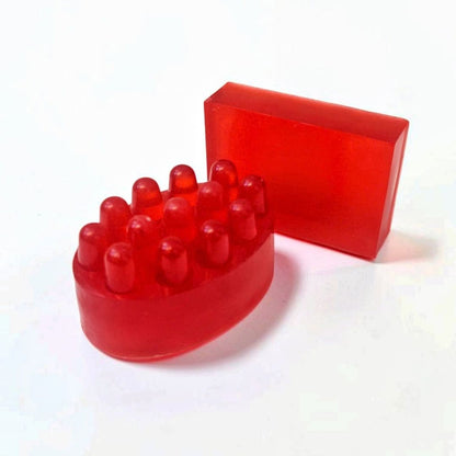 Red massage soap bar with raised massage bumps alongside a matching rectangular soap bar.