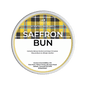 Scented wax melt container labeled 'Saffron Bun' with tartan pattern on a green background