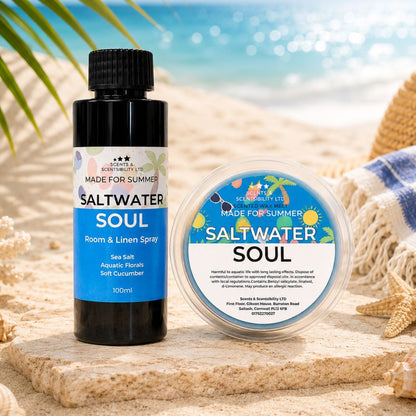 A black room and linen spray bottle and matching wax melt with colorful labels are arranged on a wooden surface with a beach backdrop. The labels read Saltwater Soul, with 'Made for Summer' printed at the top of each bottle.