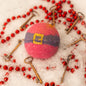 A red, round bath bomb with handpainted belt detail, surrounded by stylistic keys