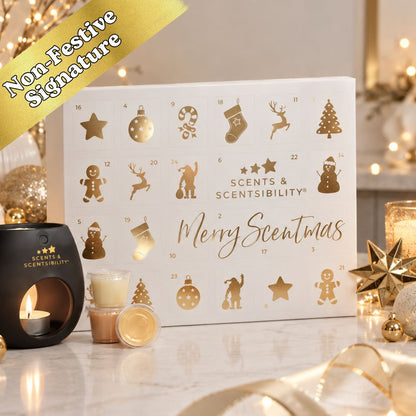 A white Christmas advent calendar with gold holiday icons and the text 'Merry Scentmas' and 'Scents & Scentsibility' on the front, styled on a tabletop with candles, gold ornaments, and warm blurred lights in the background. A gold banner in the top left reads 'Non-Festive Signature'.