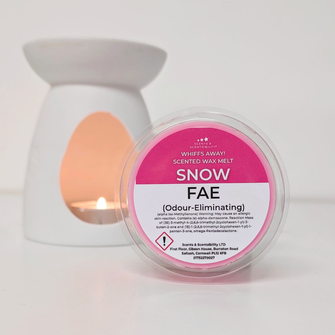 Scented wax melt container labeled 'Snow Fae' with a lit candle in the background.
