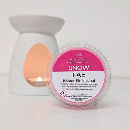 Scented wax melt container labeled 'Snow Fae' with a lit candle in the background.