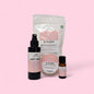 Collection of Soft Rose & Oudh products including a bottle, spray, and essential oil on a pink background.