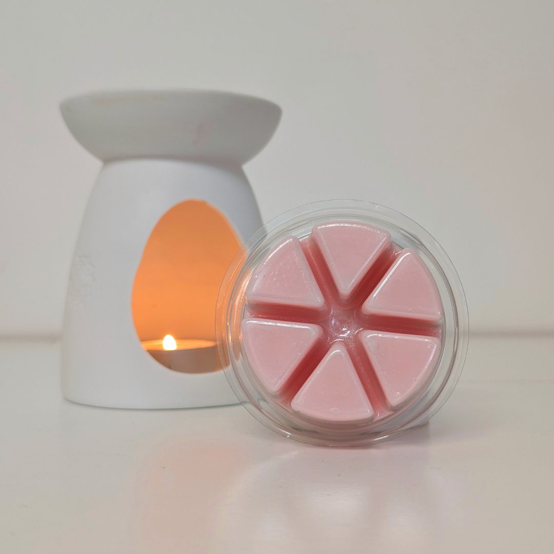 White wax warmer with a pink wax melt in a clear container on a white background