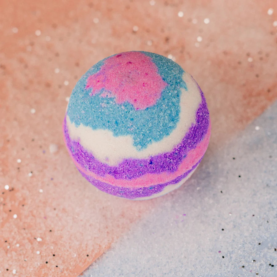 A round bath bomb with white, purple, pink and blue colours. 