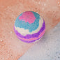 A round bath bomb with white, purple, pink and blue colours. 