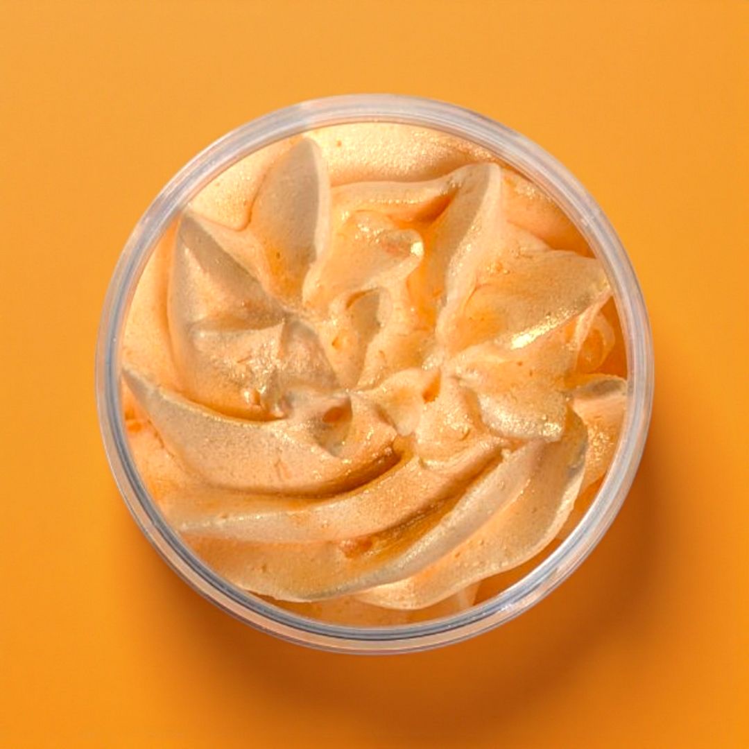 Orange whipped soap in a clear container on an orange background