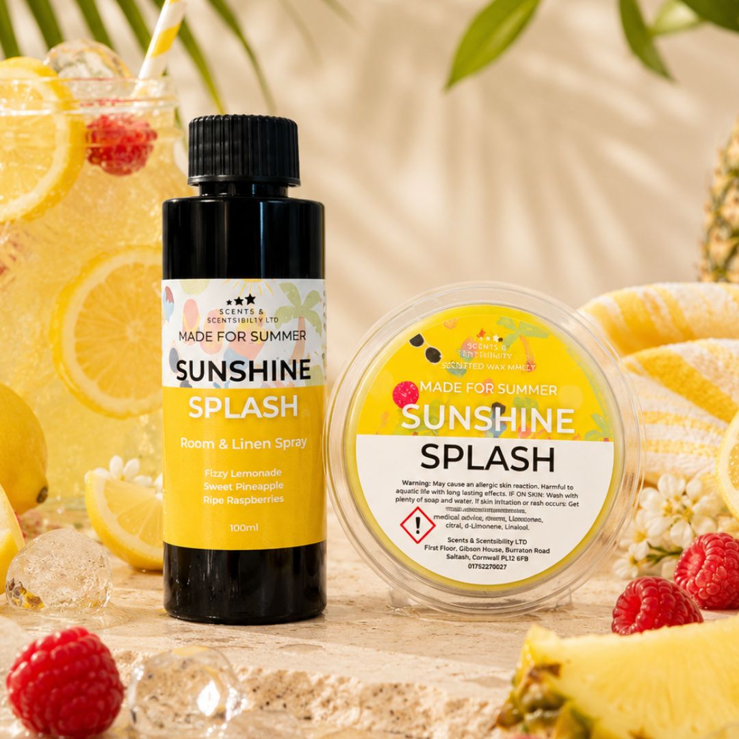 A room spray bottle and wax melt of Sunshine Splash, styled with lemon slices, raspberries, ice, and tropical leaves on a light wooden surface.