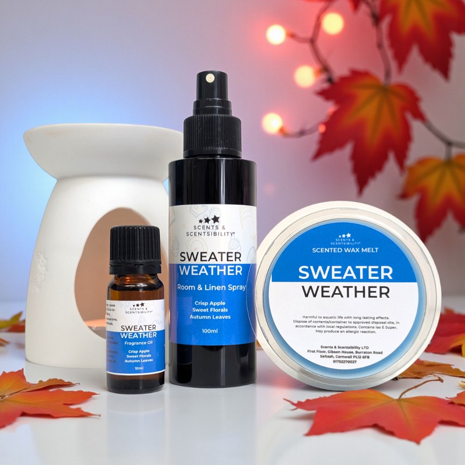 Scentsability Sweater Weather products including a room spray bottle, wax melt, and fragrance oil on a surface with autumn leaves.