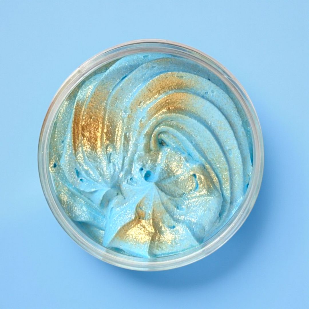 Blue and gold swirled whipped soap in a container on a blue background