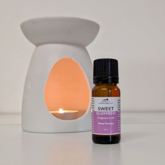 Fragrance oil bottle labeled 'Sweet Slumber' next to a lit wax warmer on a white background