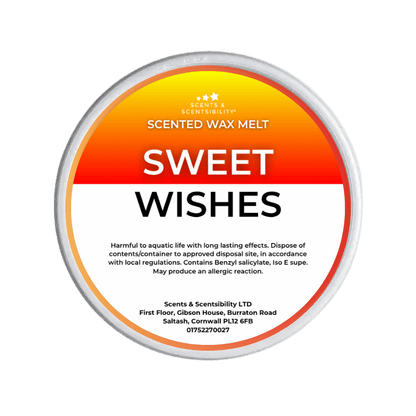 A Scents & Scentsibility 'Sweet Wishes' scented wax melt, featuring a white label with a vibrant orange-to-yellow gradient top section and black text, set against a solid dark green background.