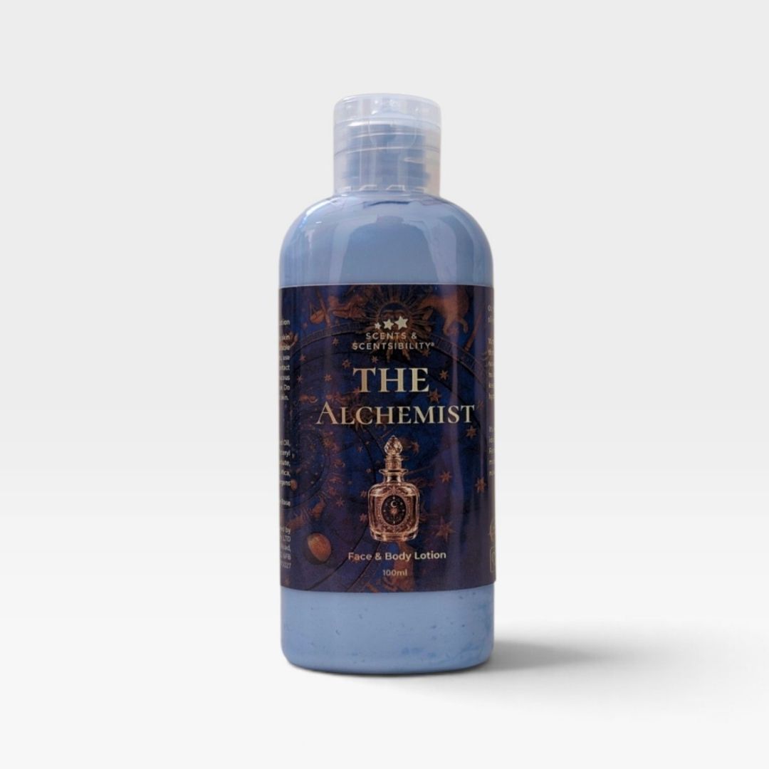 A bottle of 'The Alchemist' Face & Body Lotion by Scents & Scentsibility, featuring a light blue translucent liquid and a dark label with gold lettering, set against a plain light gray background.