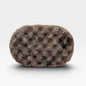 A textured, oval-shaped bath sponge with a mottled pattern of brown, beige, and black spongy material, shown on a clean white background with a soft drop shadow.