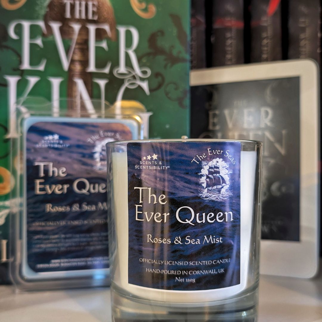 Candle labeled 'The Ever Queen' with packaging and books in the background