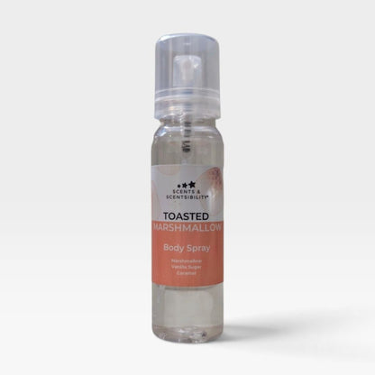 A clear plastic pump bottle of Scents & Scentsibility 'Toasted Marshmallow' body spray, showing a clear liquid inside, set against a plain light gray background.