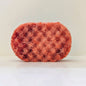 A textured dark orange sponge, filled with soap.