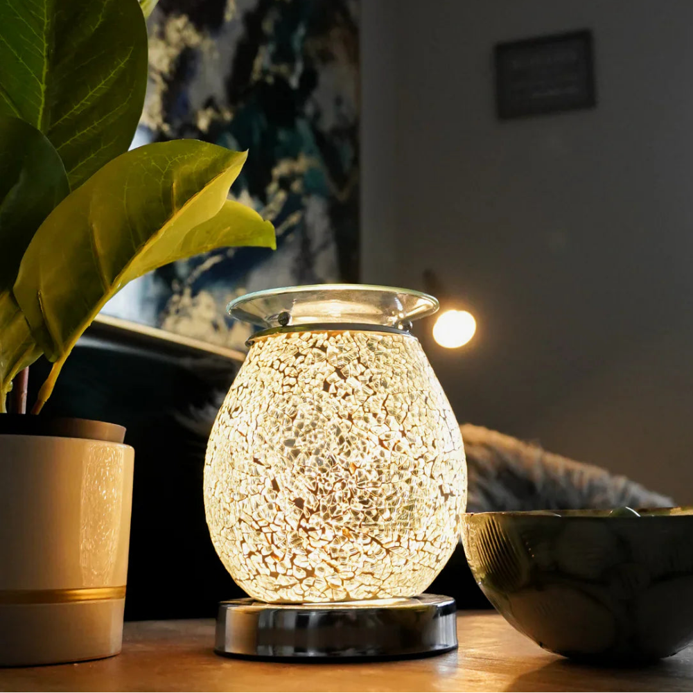 Decorative wax melt warmer on a table with a plant and bowl in a home setting