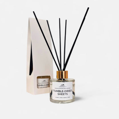 Diffuser with black reeds and a white label on a light gray background