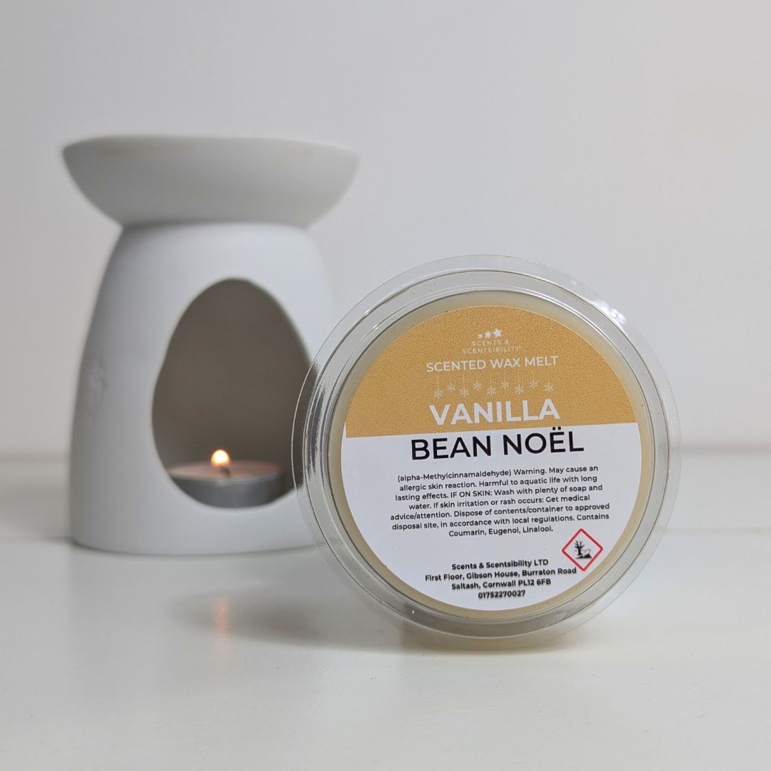 Scented wax melt container labeled 'Vanilla Bean Noel' with a white wax melt burner in the background.